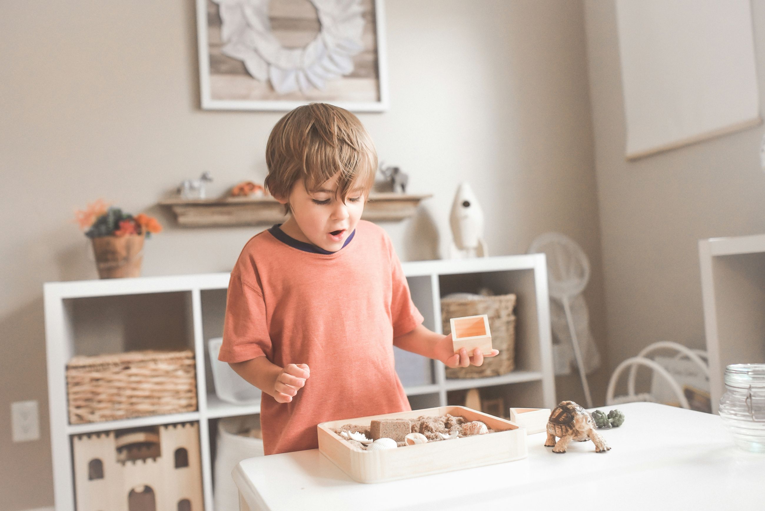 A child playing with a sand tray and small toys